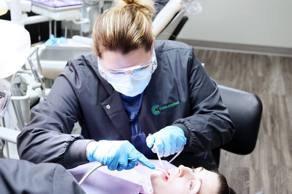 Caris College dental assisting student practicing skills on patient