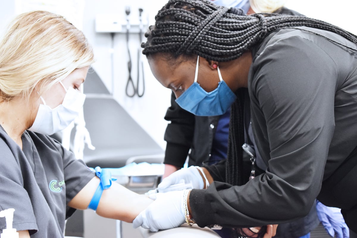 Medical Assisting student practicing blood draw on fellow student